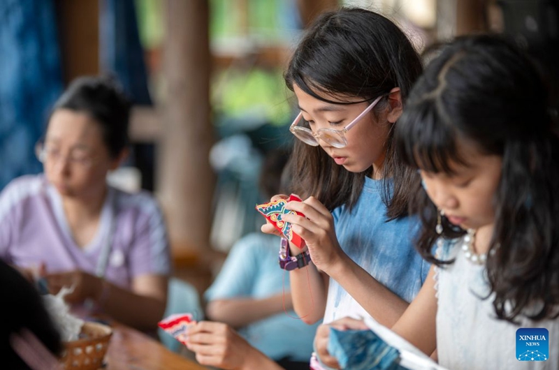 Children from Shenzhen learn to make sachet in Meide Village of Congjiang County, Qiandongnan Miao and Dong Autonomous Prefecture, southwest China's Guizhou Province, July 15, 2026. In the summer vacation, a surging number of students from big cities like Shanghai and Shenzhen come to Meide Village of Qiandongnan Miao and Dong Autonomous Prefecture for a study tour, living with local people and experiencing the culture and customs of the Dong ethnic group. Photo: Xinhua