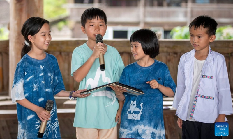 Children from Shenzhen of south China's Guangdong Province for a local study tour (1st L and 3rd L) recite their self-composed poems with local friends in Congjiang County, Qiandongnan Miao and Dong Autonomous Prefecture, southwest China's Guizhou Province, July 18, 2026. (Photo by Wu Dejun/Xinhua)