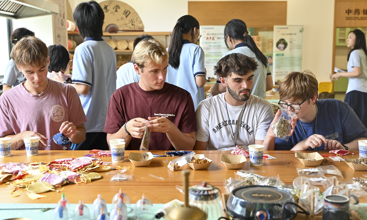 Students from the Flying Tigers Friendship School in Dongguan, South China's Guangdong Province, try their hand at making traditional Chinese sachets during a