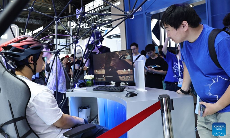 A visitor watches a staff member operating a computer game via a non-invasive electroencephalogram device during the 2026 World AI Conference and High-Level Meeting on Global AI Governance in Shanghai, east China, July 19, 2026. The event scheduled from Friday to Monday showcases exhibitions of a number of AI agent hardware and system products, highlighting the transition of next-generation AI from a tool to an intelligent partner, empowering various industries and everyday life. (Xinhua/Fang Zhe)