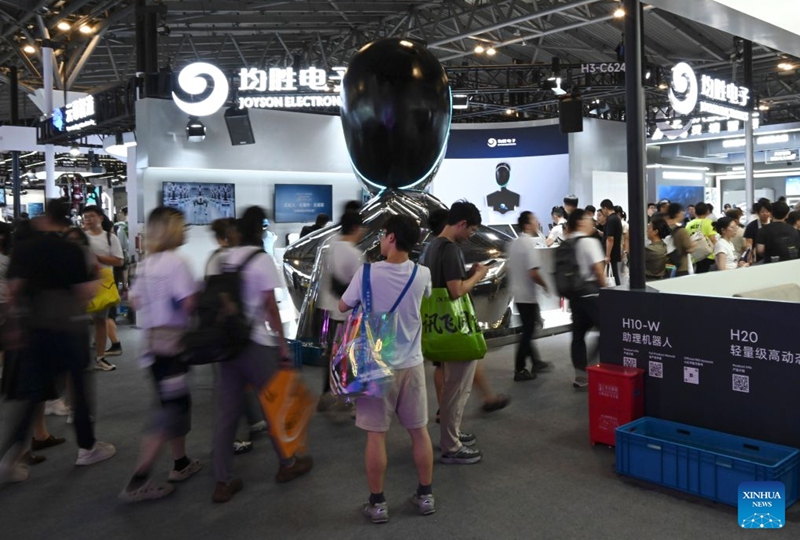 Visitors are seen in front of a robot company's booth during the 2026 World AI Conference in Shanghai, east China, July 19, 2026. The ongoing 2026 World AI Conference turns out to be a highly competitive arena for general embodied AI products from more than 200 providers. It refers to a general-purpose intelligence system that enables robots to perform variable tasks and adapt to different application scenarios. (Xinhua/Huang Xiaoyong)