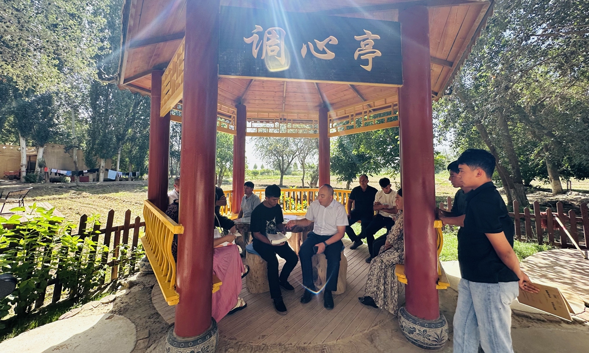 Villagers gather around township officials and counselors to discuss college application strategies for local students at the Heart-Calming Courtyard in Daoxiang Village, Hotan County, on June 26, 2026. Photo: Lin Xiaoyi/GT