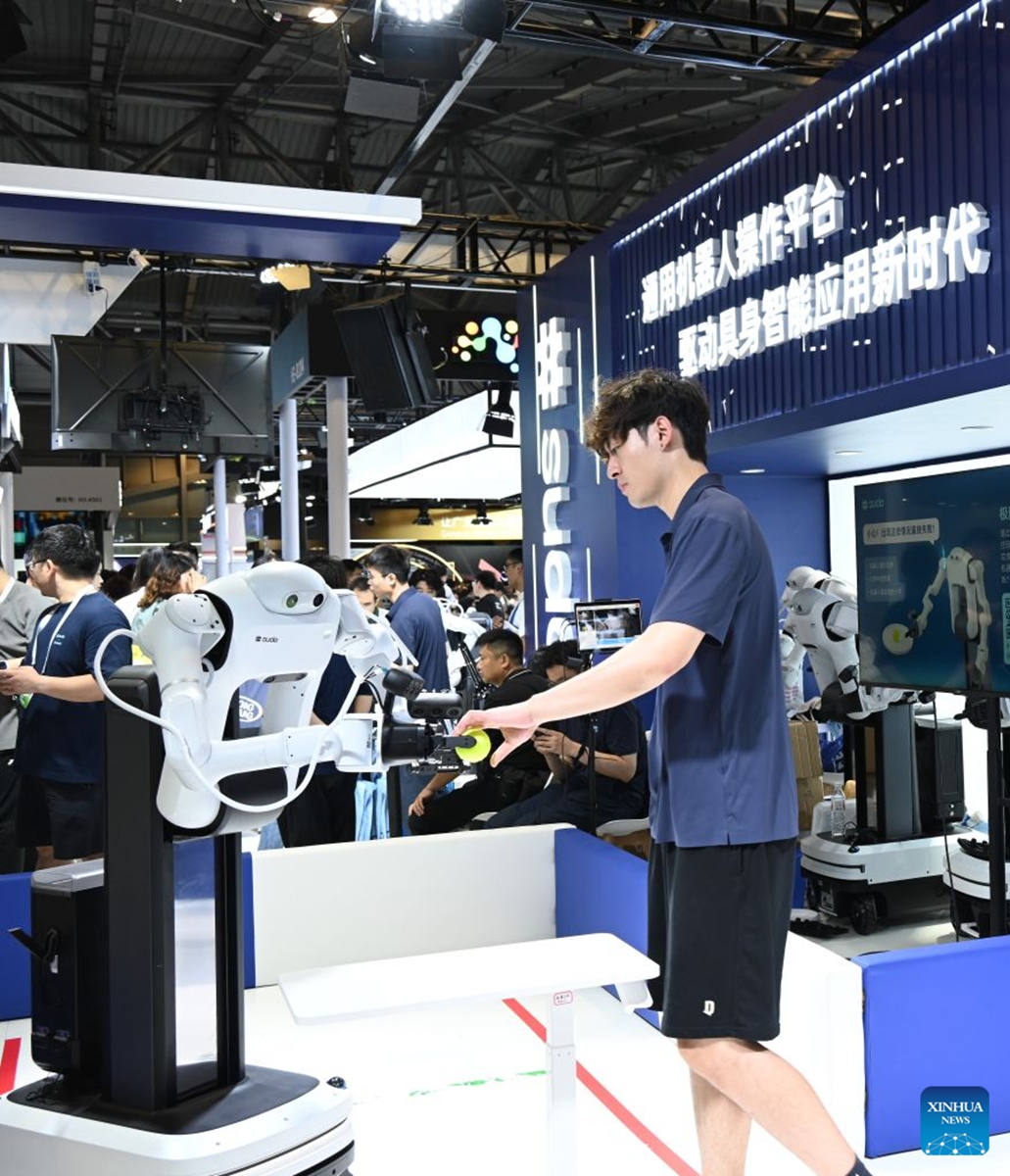 A robot takes over an object from a staff member during the 2026 World AI Conference in Shanghai, east China, July 19, 2026. The ongoing 2026 World AI Conference turns out to be a highly competitive arena for general embodied AI products from more than 200 providers. It refers to a general-purpose intelligence system that enables robots to perform variable tasks and adapt to different application scenarios. (Xinhua/Huang Xiaoyong)