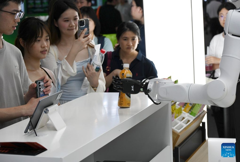 A robot hands beverage to visitors during the 2026 World AI Conference in Shanghai, east China, July 19, 2026. The ongoing 2026 World AI Conference turns out to be a highly competitive arena for general embodied AI products from more than 200 providers. It refers to a general-purpose intelligence system that enables robots to perform variable tasks and adapt to different application scenarios. (Xinhua/Huang Xiaoyong)
