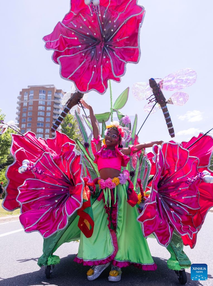A dressed-up girl poses for photos with her float during the Junior Carnival Parade of the 2026 Toronto Caribbean Carnival in Toronto, Canada, on July 19, 2026. Thousands of young participants in vivid costumes took part in the parade, celebrating Caribbean culture through music and dance. (Photo by Zou Zheng/Xinhua)