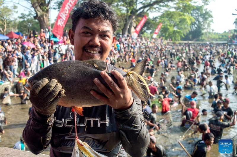 A man presents a fish he caught during Festival Memet Ikan, or fish catching festival, at Gemblegan village in Klaten regency, Central Java, Indonesia, July 19, 2026. (Photo by Agung Supriyanto/Xinhua)