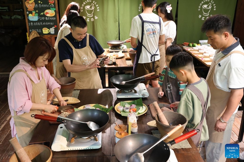 Tourists learn to cook specialty dishes of the Dai ethnic group in Jinghong City, southwest China's Yunnan Province, July 19, 2026. (Photo by Li Yunsheng/Xinhua)