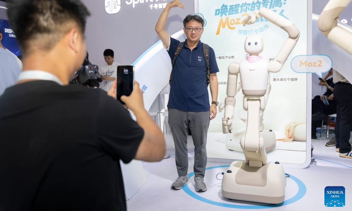 A visitor and a humanoid robot make heart gestures as they pose for photos during the 2026 World AI Conference and High-Level Meeting on Global AI Governance in Shanghai, east China, July 20, 2026. The 2026 World AI Conference and High-Level Meeting on Global AI Governance concluded here on Monday. (Xinhua/Wang Xiang)