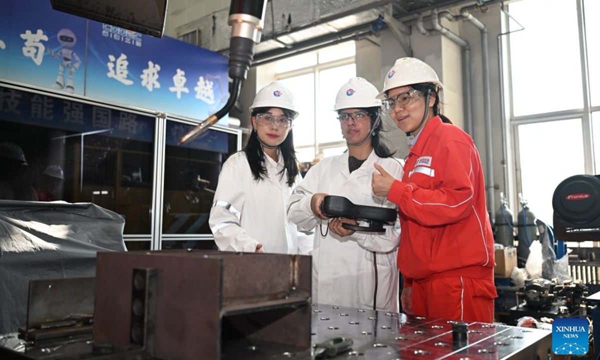 Rimaz Dakhilallah Aljohani (C) tries welding at the Tianjin Intelligent Manufacturing Branch of Offshore Oil Engineering Co., Ltd. (COOEC) in Tianjin, north China, July 9, 2026. Rimaz Dakhilallah Aljohani, a 22-year-old junior majoring in petroleum engineering at King Fahd University of Petroleum and Minerals (KFUPM) in Saudi Arabia, began a two-month internship and training program with six of her classmates at Offshore Oil Engineering Co., Ltd. (COOEC) in Tianjin during the summer vacation. (Xinhua/Sun Fanyue)
