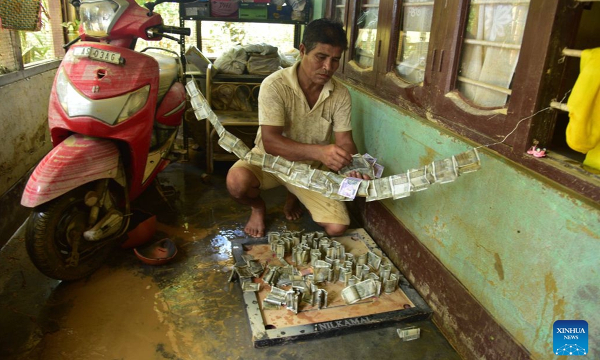 A villager dries banknotes at his house besieged by floodwaters after heavy rains in Jorhat district of India's northeastern state of Assam, on July 21, 2026. (Str/Xinhua)