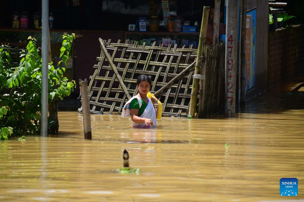 A villager wades through floodwaters after heavy rains in Jorhat district of India's northeastern state of Assam, on July 21, 2026. (Str/Xinhua)
