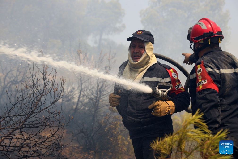 Firefighters work against a wildfire on a mountain in El Hachimia, northern Algeria, on July 21, 2026. Six people have been killed in wildfires sweeping across northern Algeria as a prolonged heat wave continues to fuel forest and vegetation fires in several provinces, the Algerian Ministry of the Interior, Local Authorities and Transports said Tuesday. (Photo by Billel Bensalem/Xinhua)