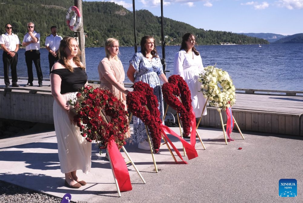 Representatives stand beside wreaths during a memorial event marking the 15th anniversary of the July 22, 2011 terror attacks on Utoya Island, Norway, July 22, 2026. Norwegian Prime Minister Jonas Gahr Store on Wednesday warned of the growing threat of far-right radicalization among young people, saying social media, artificial intelligence and social isolation were fueling extremism, as the country marked the 15th anniversary of the July 22, 2011 terror attacks. (Xinhua/Zhang Yuliang)