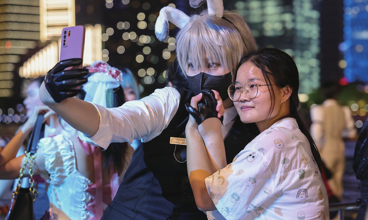 A woman poses for a picture with a cosplayer.