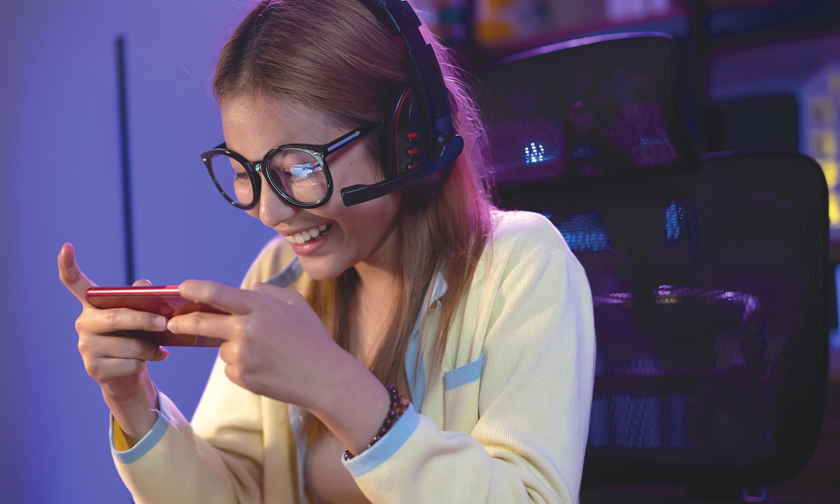 A young woman plays a mobile game. Photos on this page: VCG 