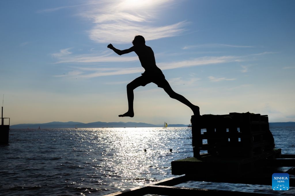 A boy jumps into the sea to cool off in Vladivostok, Russia, July 22, 2026. (Photo by Andrey Matveenko/Xinhua)