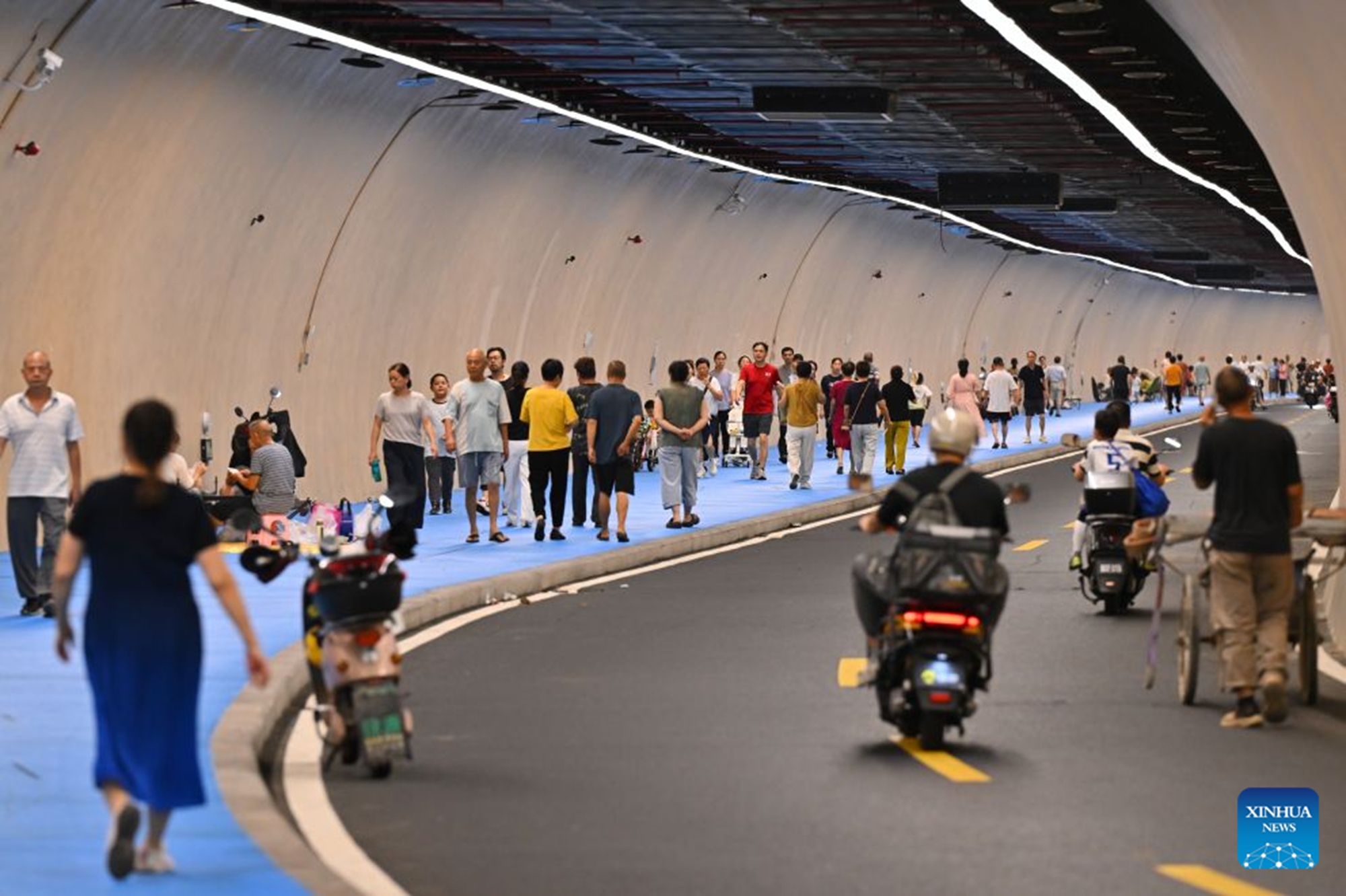 Residents relax at an air-raid shelter to cool off in Fuzhou, southeast China's Fujian Province, July 23, 2026. As summer temperatures soar, Fuzhou has made some tunnels, air-raid shelters and metro stations available as public cooling spaces. Equipped with benches, chairs and other convenience facilities, these sites have become popular for residents to relax and escape the heat. (Xinhua/Jiang Kehong)