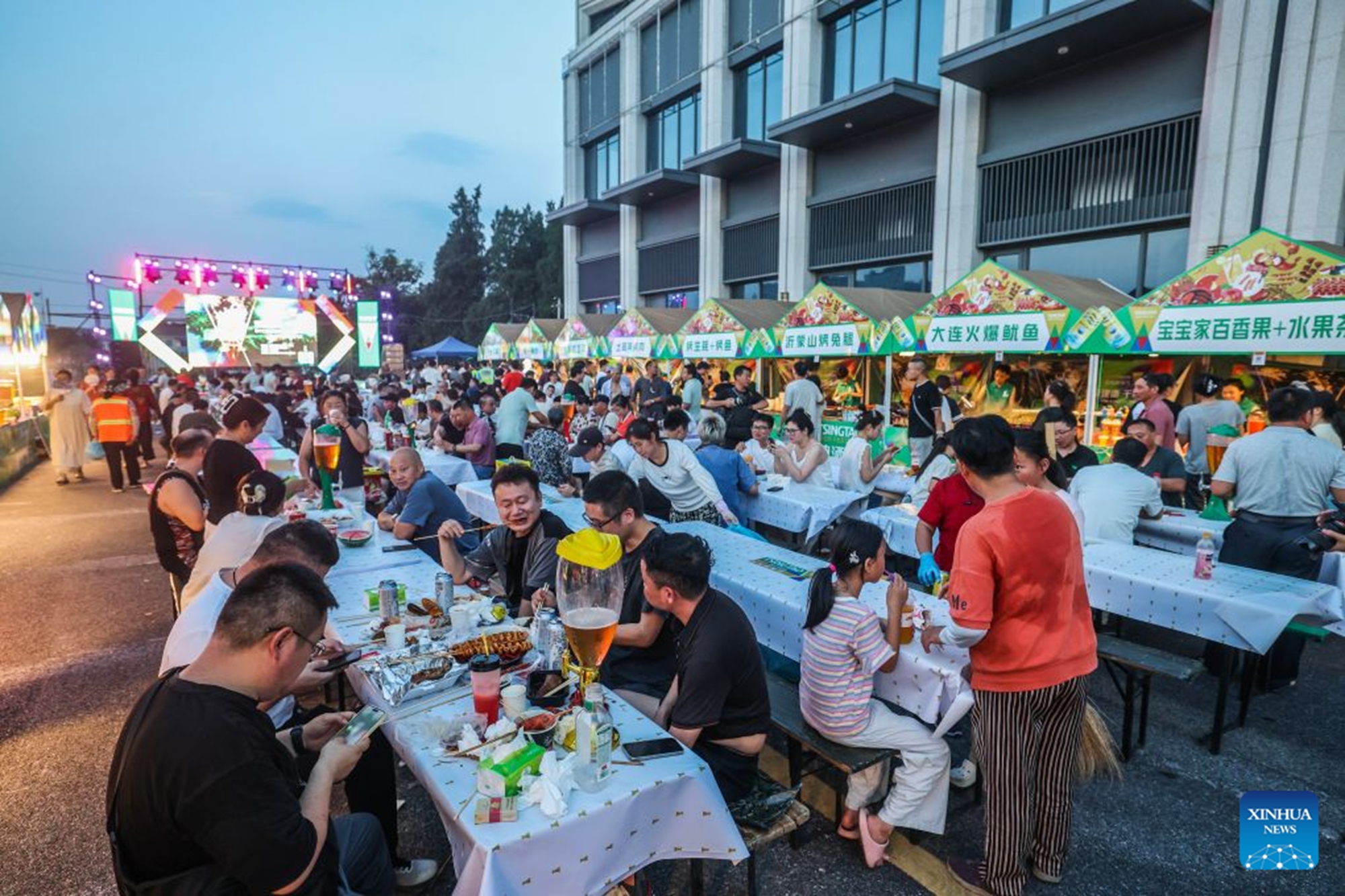 An aerial drone photo taken on July 24, 2026 shows people enjoying foods and drinks at a beer festival in Jiande City of east China's Zhejiang Province. A summer beer festival kicked off at a farmers market here on Friday. Featuring live performances, gourmet foods and drinks, leisure activities and bazaars, the event attracted thousands of locals and tourists. (Xinhua/Xu Yu)
