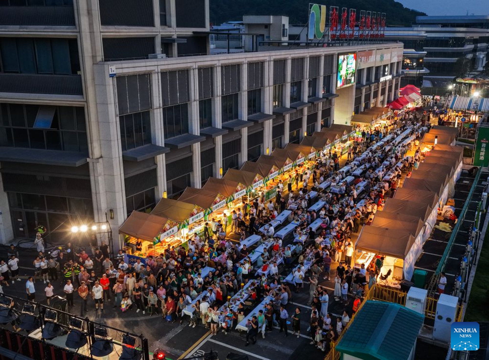 An aerial drone photo taken on July 24, 2026 shows people enjoying foods and drinks at a beer festival in Jiande City of east China's Zhejiang Province. A summer beer festival kicked off at a farmers market here on Friday. Featuring live performances, gourmet foods and drinks, leisure activities and bazaars, the event attracted thousands of locals and tourists. (Xinhua/Xu Yu)