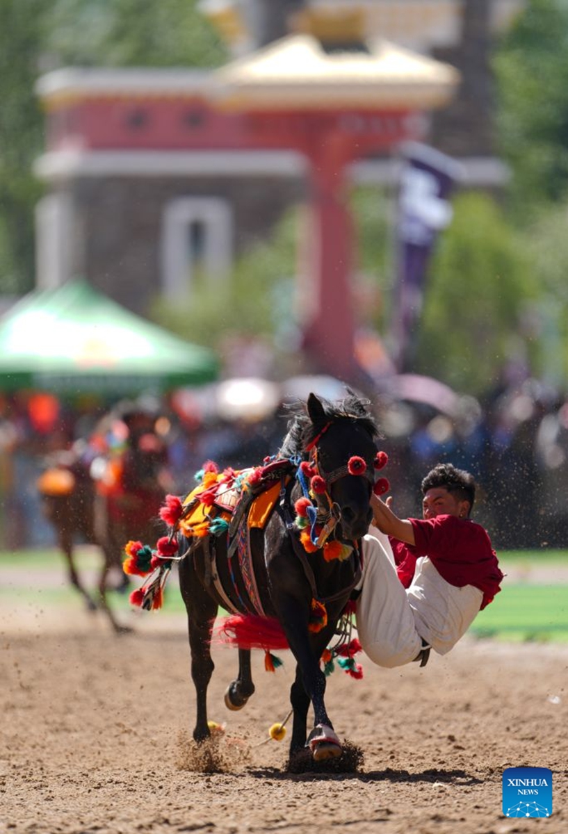 A rider shows off equestrian stunts during the opening ceremony of the 44th Yushu horse racing festival in Yushu Tibetan Autonomous Prefecture, northwest China's Qinghai Province, July 25, 2026. The festival kicked off here on Saturday, and will last until August. (Xinhua/Du Xiaowei)