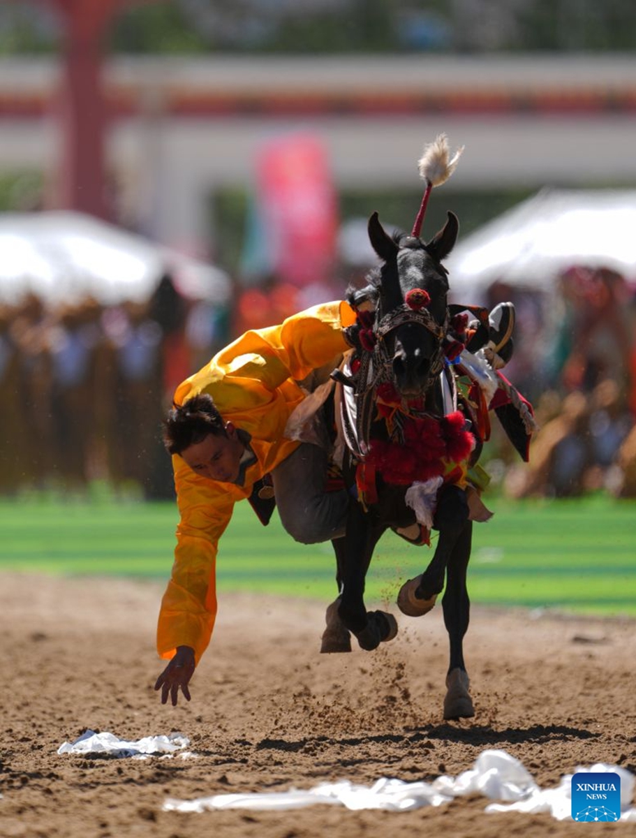 A rider shows off equestrian stunts during the opening ceremony of the 44th Yushu horse racing festival in Yushu Tibetan Autonomous Prefecture, northwest China's Qinghai Province, July 25, 2026. The festival kicked off here on Saturday, and will last until August. (Xinhua/Du Xiaowei)