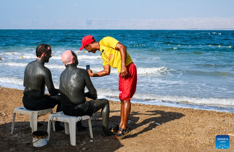 Tourists apply Dead Sea mud to their bodies near the Dead Sea in Jordan, on July 25, 2026. The Dead Sea has been experiencing a long-term decline in its water level due to reduced inflow from the Jordan River, the region's naturally high evaporation rates, and industrial mineral extraction. Available data show that as of July 2026, the Dead Sea's surface was approximately 440 meters below sea level, and its water level has been declining by an average of more than one meter annually. (Xinhua/Xin Mengchen)