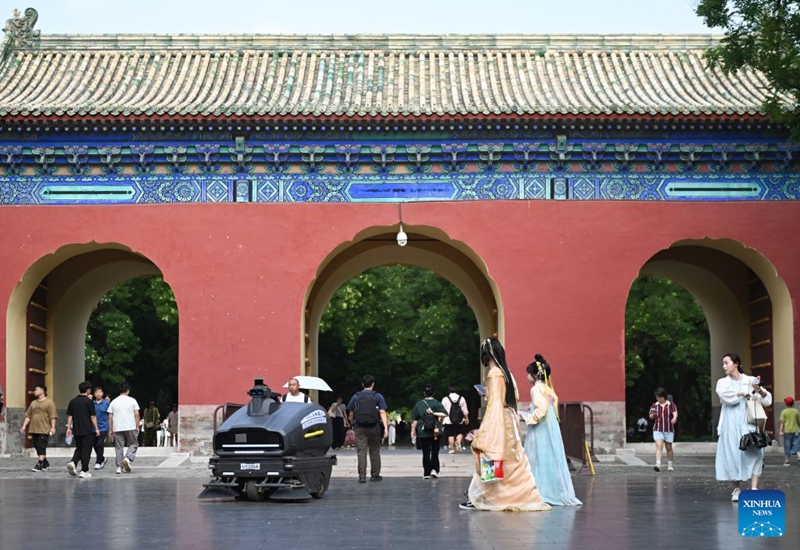 Tourists dressed in traditional Chinese attire encounter with a cleaning robot at the Temple of Heaven Park in Beijing, capital of China, July 24, 2026. Marking the second anniversary of the successful inscription of the Beijing Central Axis on the UNESCO World Heritage List, heritage sites along the Beijing Central Axis, such as the Palace Museum, Zhengyangmen Gate, and Altar of the God of Agriculture, also referred to as the Xiannongtan Temple, will either open to the public free of charge or launch new exhibitions on July 27.
Over the past two years, efforts to conserve, inherit and make good use of the Beijing Central Axis have advanced steadily, achieving new outcomes in areas including related legal system, UNESCO World Heritage signage, landscape improvement, creative utilization, collaborative protection and international communication. Photo: Xinhua