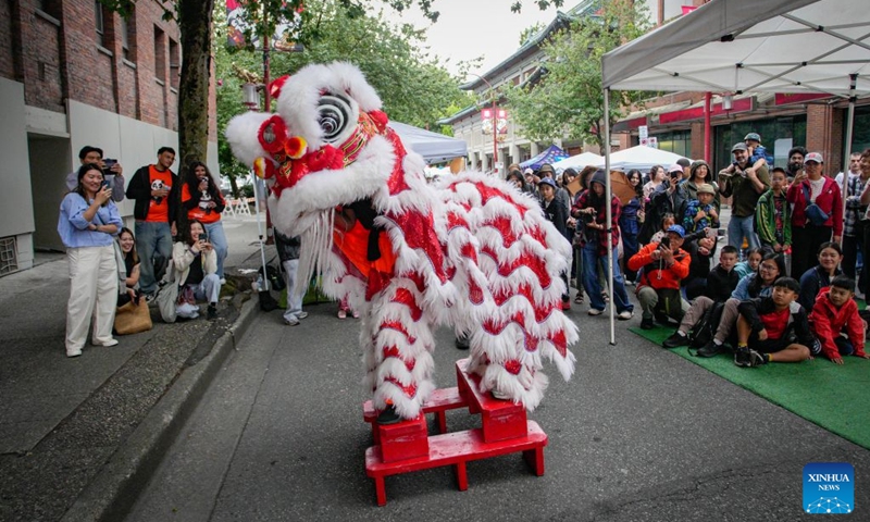 People watch a lion dance performance during the Chinatown Festival in Vancouver, British Columbia, Canada, July 25, 2026. The two-day cultural festival kicked off here on Saturday, celebrating the heritage of Vancouver's historic Chinatown with traditional cultural performances, local food vendors and family-friendly activities. (Photo by Liang Sen/Xinhua)