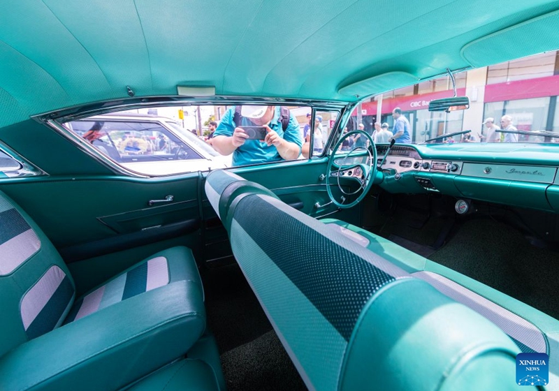 A man takes photos of a vintage car on display at the Dream Wheels on Eglinton 2026 in Toronto, Canada, July 25, 2026. The event was held here on Saturday featuring a curated showcase of classic cars. (Photo by Zou Zheng/Xinhua)