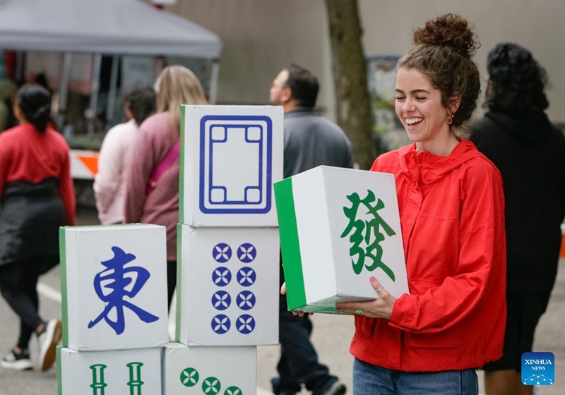 A visitor participates in a mahjong-themed activity during the Chinatown Festival in Vancouver, British Columbia, Canada, July 25, 2026. The two-day cultural festival kicked off here on Saturday, celebrating the heritage of Vancouver's historic Chinatown with traditional cultural performances, local food vendors and family-friendly activities. (Photo by Liang Sen/Xinhua)