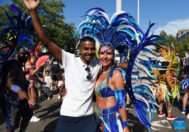 A man has a photo with a dancer during the Rotterdam Summer Carnival, which was inscribed on UNESCO's Intangible Cultural Heritage, in Rotterdam, the Netherlands, July 25, 2026. (Xinhua/Shao Haijun)