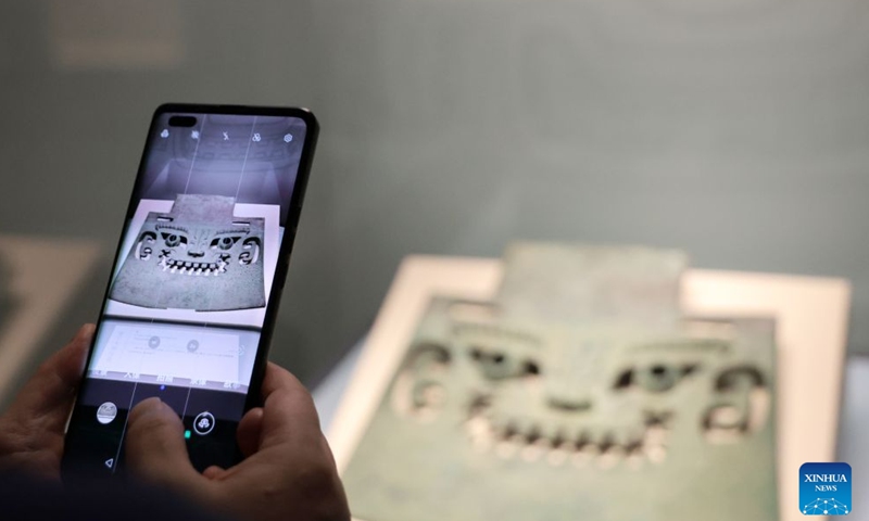 A visitor takes a photo at the exhibition Smiles: Imprints of the Chinese Spirit in Cultural Relics at the Liaoning Provincial Museum in Shenyang, northeast China's Liaoning Province, July 26, 2026.