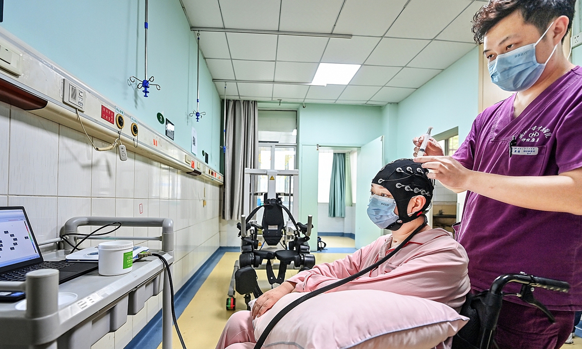 A patient surnamed Hu wears an EEG (electroence phalography) cap to control a robotic device, enabling lower-limb movemen. Photo: VCG
