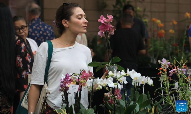 A woman looks at flowers at an orchids trade fair at Golden Gate Park of San Francisco, the United States, July 25, 2026. (Photo by Liu Yilin/Xinhua)
