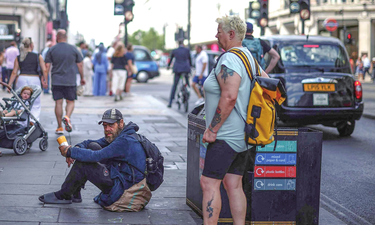 A man sits on the pavement waiting for donations from passersby along a street in London on July 28, 2026. The number of people estimated to be sleeping rough on a single night in autumn 2025 is 4,793, according to the UK government. Photo: VCG