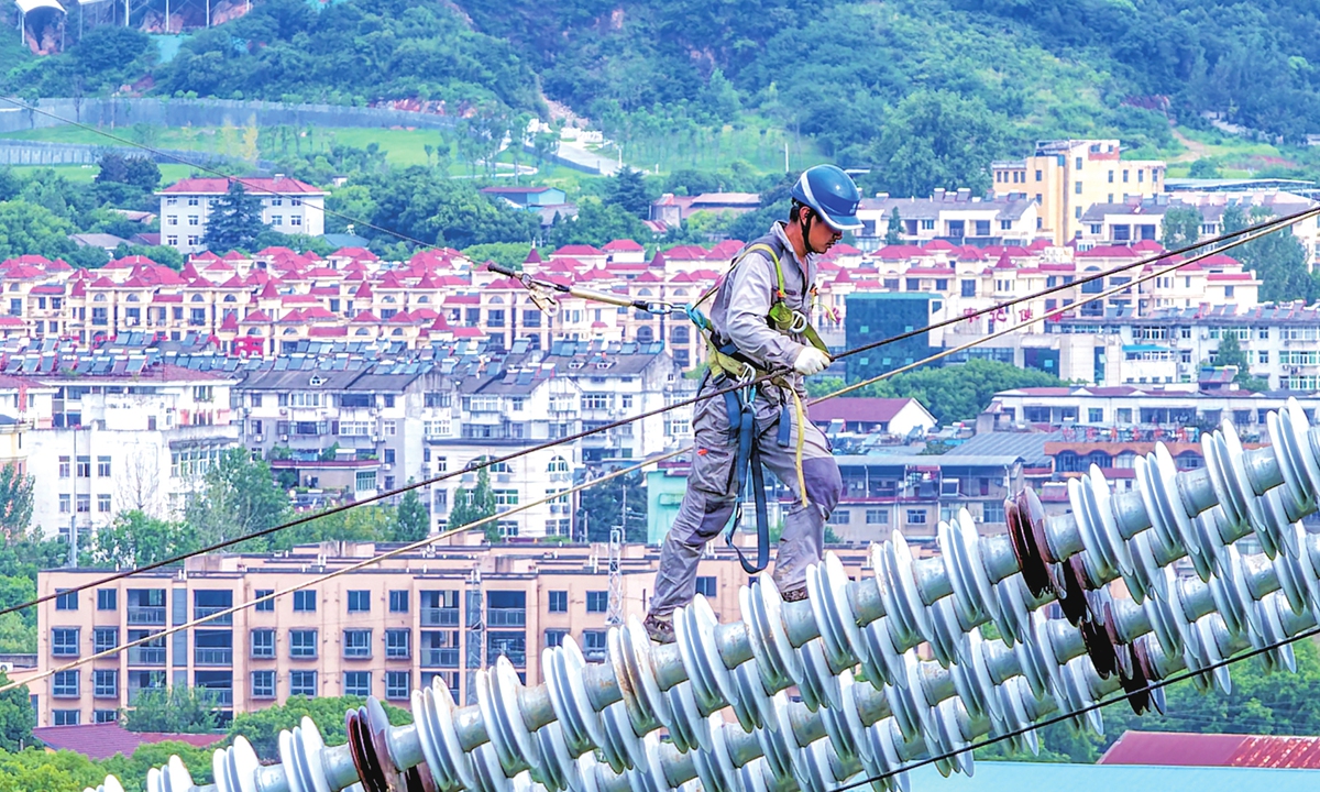 A power construction worker carries out conductor cutover operations despite intense high temperatures at a power transmission tower in Wuhu, East China's Anhui Province on July 30, 2026. The work is part of advancing a project that transmits ultra-high-voltage power from Northwest China's Gansu Province to East China's Zhejiang Province. Photo: VCG