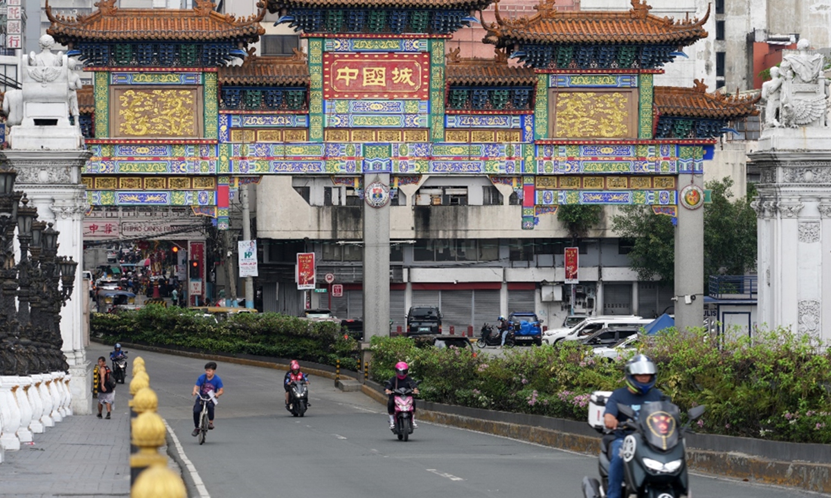 Cyclists and pedestrians pass beneath the Chinatown Arch in Binondo, Manila, the Philippines, in March 2024. Established in 1594, Binondo is widely recognized as the world's oldest Chinatown. Photo: VCG