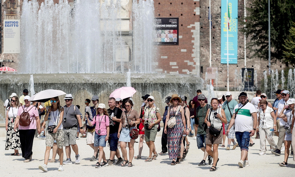 People use fans and shelter from the sun under umbrellas on a hot summer day in Milan, Italy, on July 31, 2026. The Italian Ministry of Health issued a heatwave red alert for 19 cities starting August 1. Photo: VCG