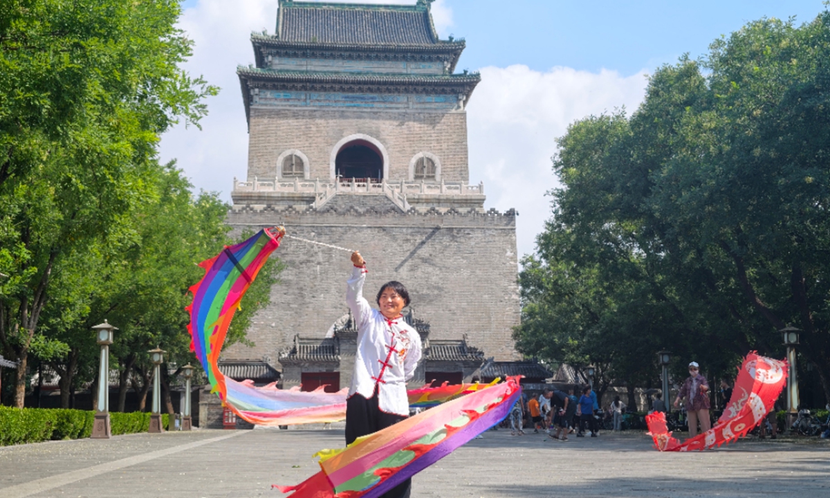 A resident twirls a colorful ribbon streamer for fitness in front of the Drum Tower, a landmark sitting on the Beijing Central Axis, on July 29, 2026. Photo: VCG