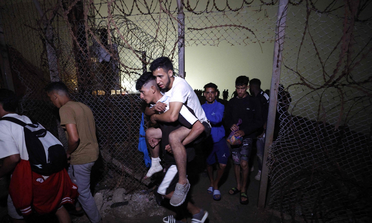 Migrants pass through a broken fence as they leave Spain's North African enclave of Ceuta towards the Moroccan town of Fnideq, on the Morocco-Spain border, following an attempted to cross at the Bab Sebta border crossing, on August 1, 2026.  Photo: VCG