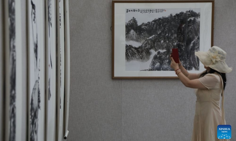 A visitor takes photos during a traditional Chinese painting exhibition in Beijing, capital of China, Aug. 1, 2026. (Xinhua/Lu Peng)
