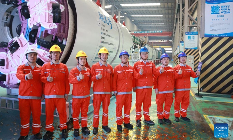 Representatives of technical workers contributed to the manufacturing of the boring and blasting machine pose for a group photo at a manufacturing base of China Railway Science & Industry Group in Wuhan, central China's Hubei Province, Aug. 1, 2026. China's first boring and blasting machine rolled off the production line here on Saturday, filling the gap in integrated tunneling equipment for tunnels with complex geological conditions. (Photo by Zhao Jun/Xinhua)