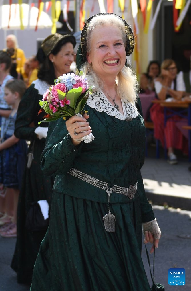 A woman participates in a traditional costume parade in Villach, Austria, Aug. 1, 2026. (Xinhua/He Canling)