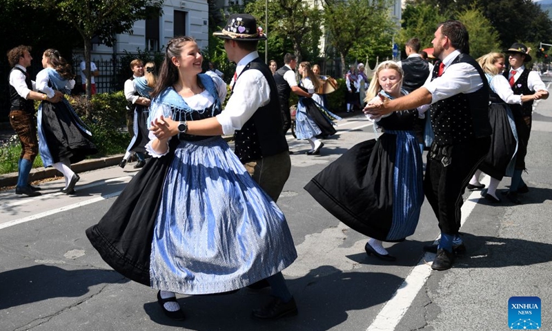 People dance during a traditional costume parade in Villach, Austria, Aug. 1, 2026. (Xinhua/He Canling)