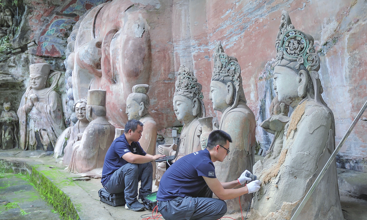 Conservators carry out testing on the Buddha statues at the Dazu Rock Carvings site in Chongqing Municipality on June 29, 2019.  Conservation expert Bai Yongqin explores a mural in North China's Shanxi Province. 
Photo: Courtesy of Bai Yongqin