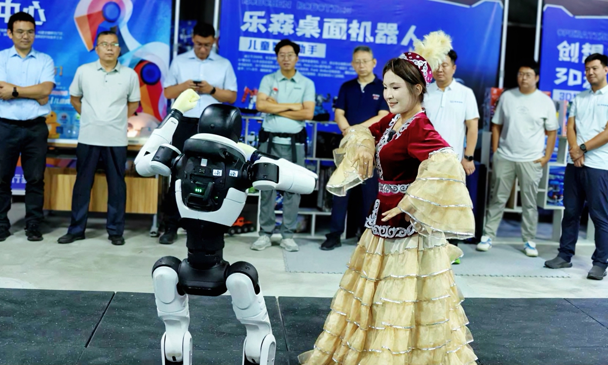 A Xinjiang local resident dances with a robot at the temporary exhibition hall at the region's first robotics 9S center on July 31, 2026. Photo: courtesy of the Xinjiang Future Era Information Technology Co, the operator of the project