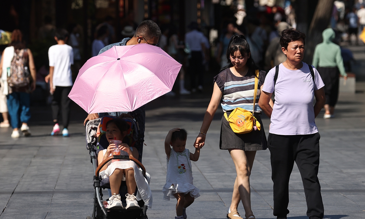 Residents walk along a street with children in Nanjing, East China's Jiangsu Province, on July 30, 2026, as persistent high temperatures continue in the city. Photo: VCG