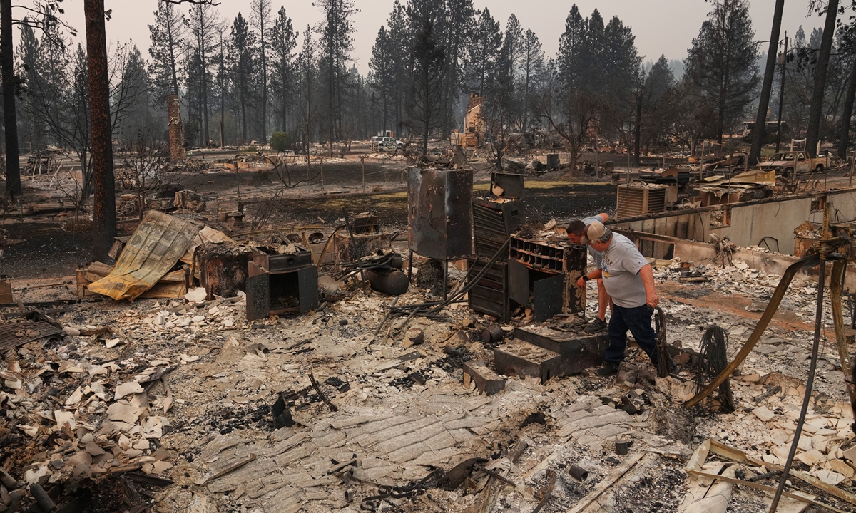 Louis Acosta (left), and father Al Acosta look through the remains of the home Al lived in for 40 years, after a wildfire destroyed neighborhoods in the northern part of Spokane, Washington on August 3, 2026. Since igniting on Saturday, the three fires in Spokane destroyed more than 700 structures and displaced tens of thousands of residents. Photo: VCG