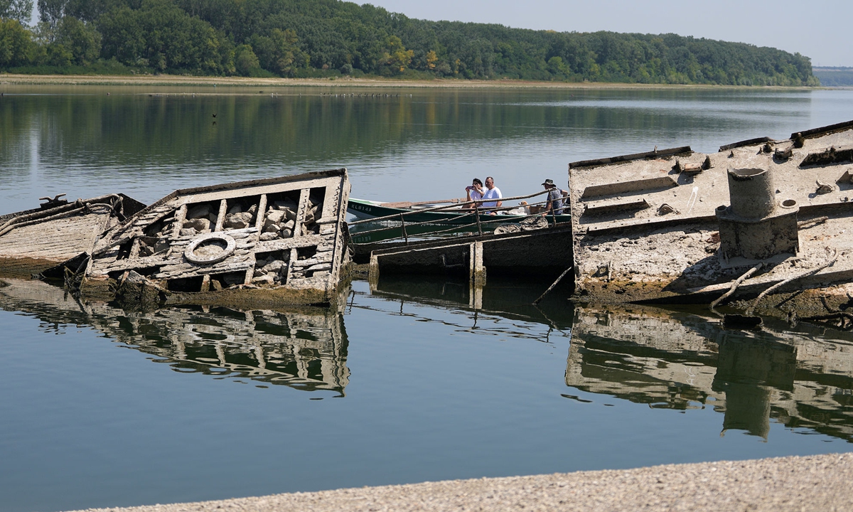 People watch the wreckage of a WWII German warship, emerged due to the drought, in front of Djerdap II, a large dam on the Danube River, between Romania and Serbia, near Prahovo, Serbia, on August 4, 2026. Photo: VCG