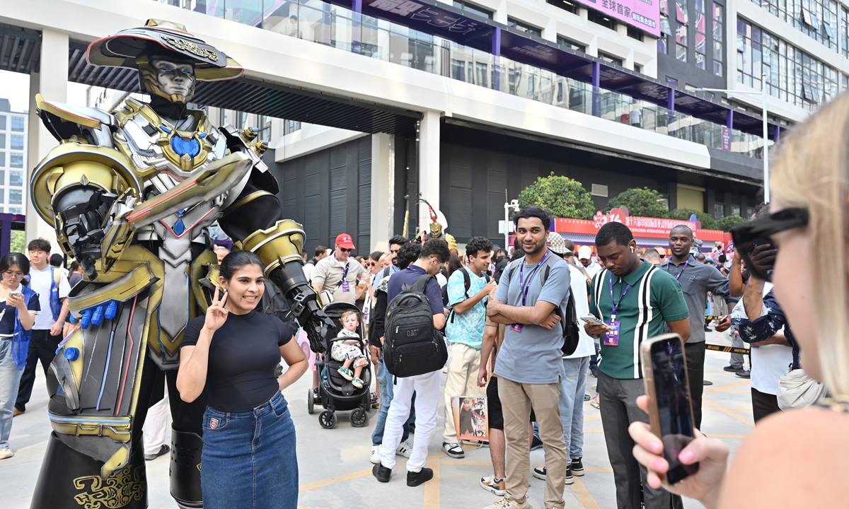 A foreign tourist poses for a photo alongside a mecha figure on display at the 2026 China International Comics & Games Expo held in Dongguan, South China's Guangdong Province, on August 6, 2026. Photo: VCG